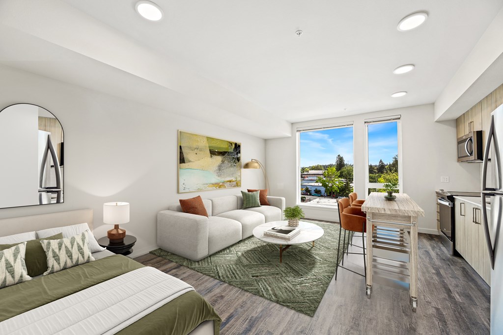 A well-lit, modern bedroom with a large bed and a kitchen area in the background.